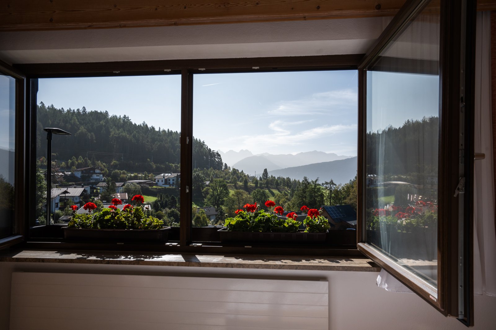 Blick aus dem Fenster mit Geranien auf die Berge